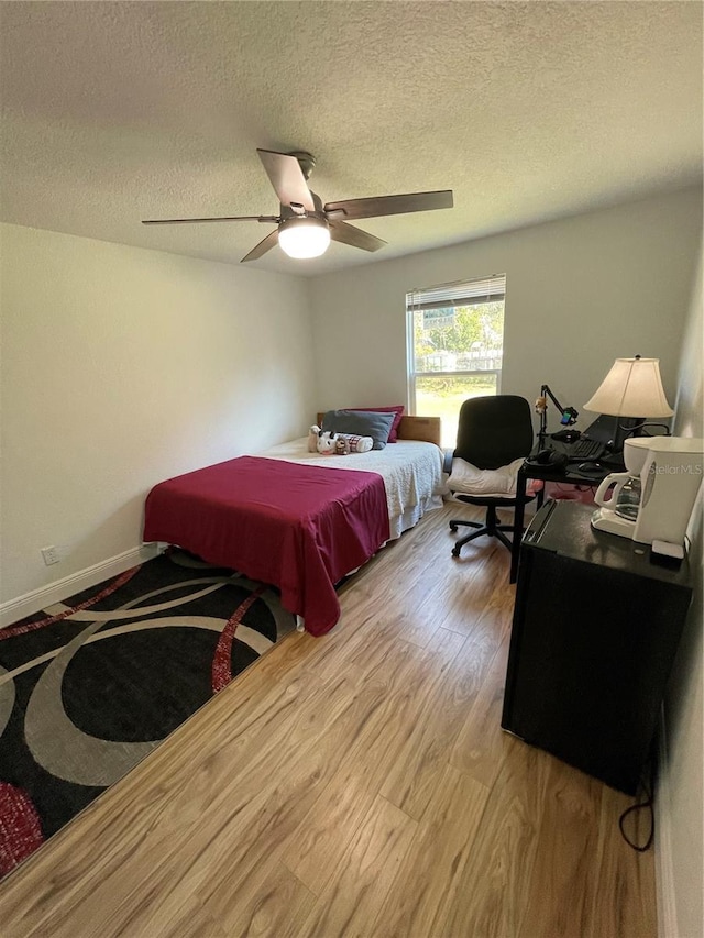 bedroom with baseboards, a textured ceiling, a ceiling fan, and light wood finished floors