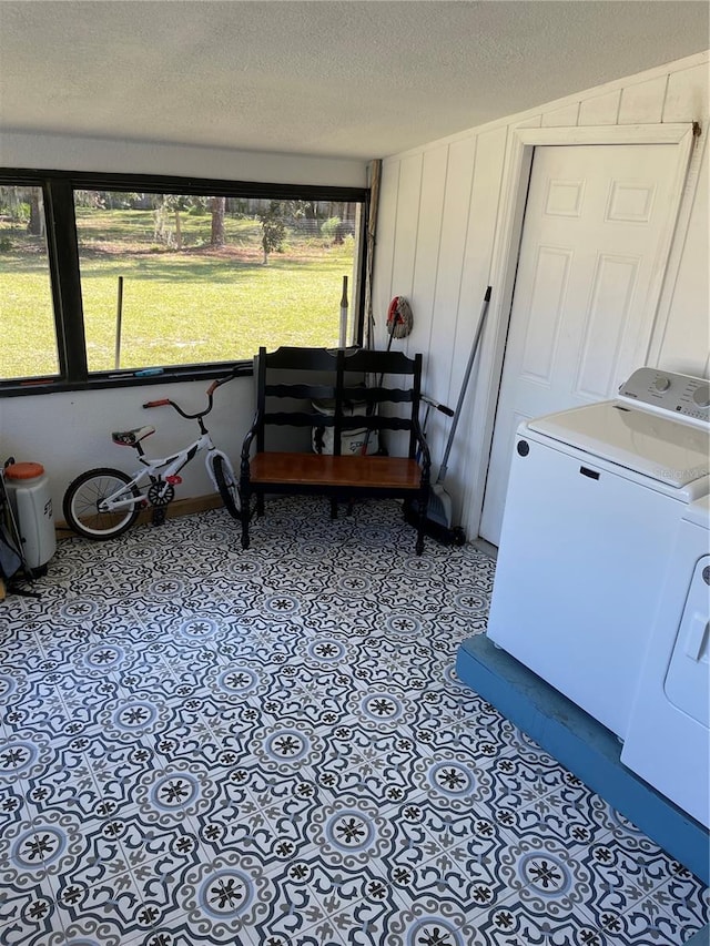 interior space with a textured ceiling, washing machine and dryer, laundry area, and tile patterned flooring