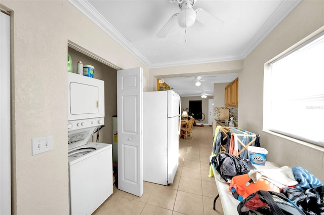 clothes washing area featuring crown molding, ceiling fan, stacked washer and clothes dryer, and light tile patterned floors