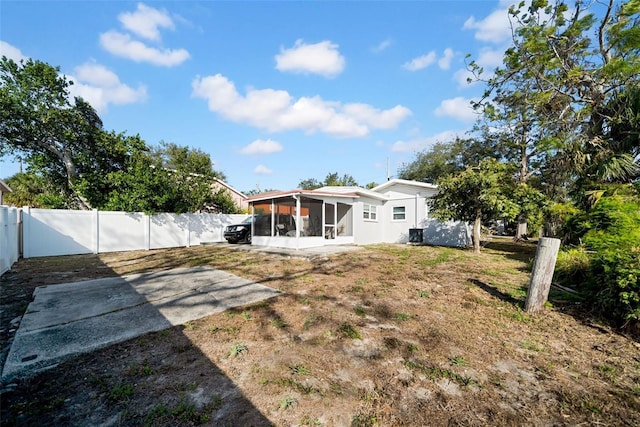 back of property featuring a lawn, a sunroom, and a patio