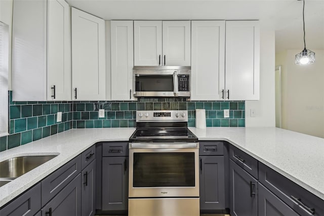 kitchen featuring appliances with stainless steel finishes, pendant lighting, tasteful backsplash, white cabinets, and light stone counters