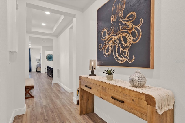 hallway featuring a raised ceiling and light wood-type flooring