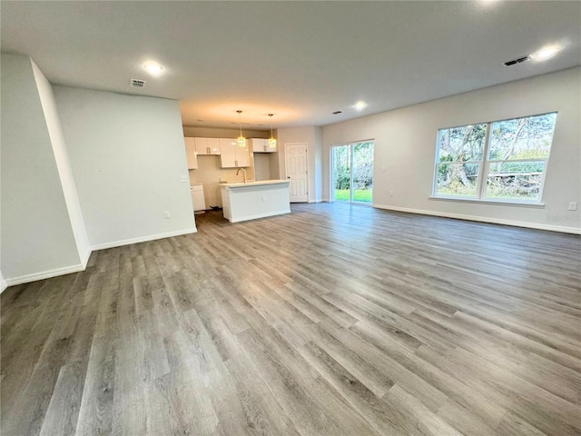 unfurnished living room with sink and light hardwood / wood-style flooring