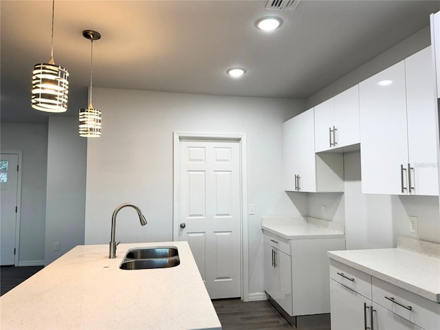 kitchen featuring sink, light stone counters, decorative light fixtures, dark hardwood / wood-style flooring, and white cabinets