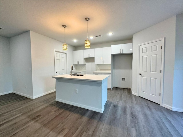 kitchen featuring sink, a center island with sink, dark hardwood / wood-style floors, pendant lighting, and white cabinets