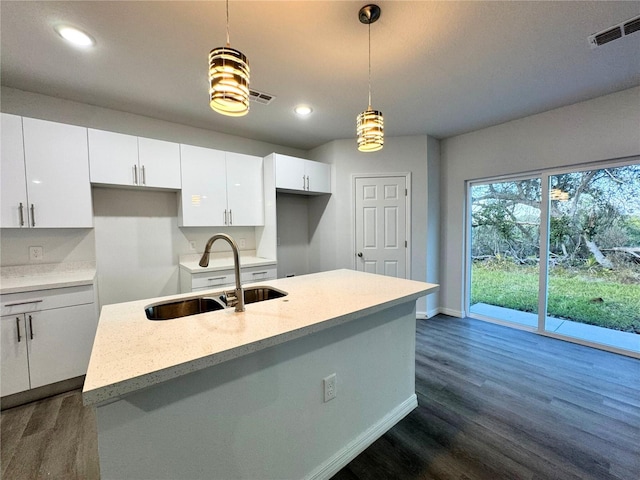 kitchen with sink, dark wood-type flooring, white cabinetry, a center island with sink, and decorative light fixtures