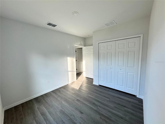 unfurnished bedroom with dark wood-type flooring and a closet