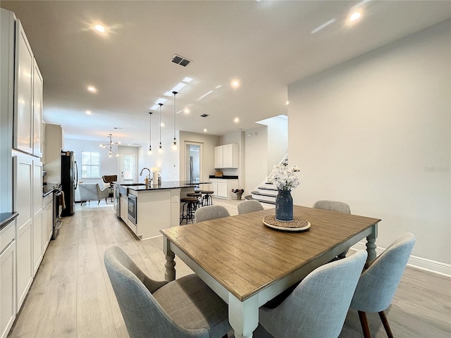 dining space with a notable chandelier and light hardwood / wood-style flooring