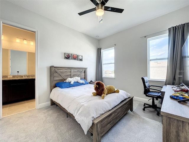 bedroom with light carpet, connected bathroom, multiple windows, and ceiling fan