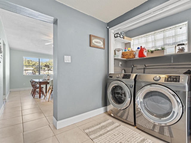 clothes washing area with washer and clothes dryer, a textured ceiling, and light tile patterned floors