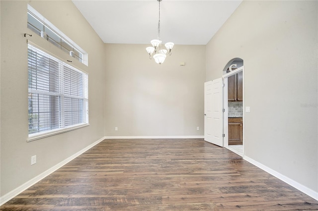 unfurnished room with a healthy amount of sunlight, a chandelier, and dark hardwood / wood-style flooring