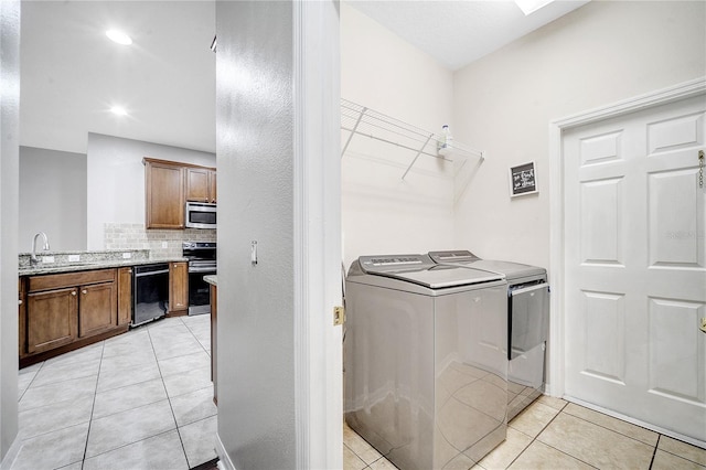 laundry area featuring separate washer and dryer, sink, and light tile patterned floors