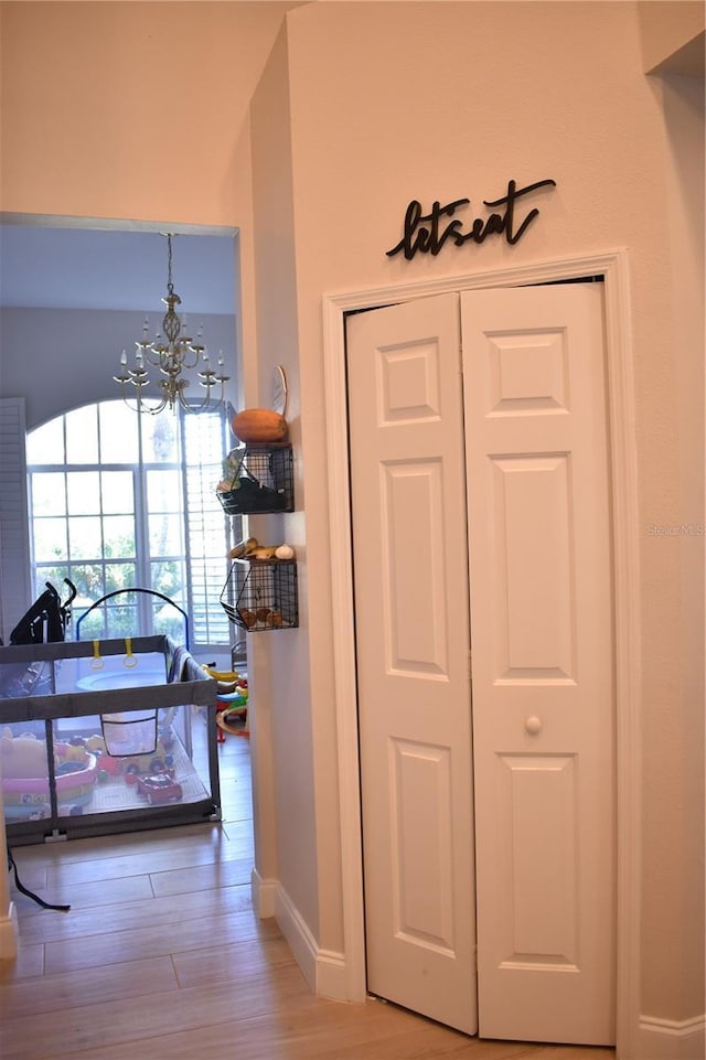 hallway featuring an inviting chandelier and light hardwood / wood-style floors