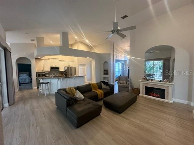 living room with light hardwood / wood-style flooring, high vaulted ceiling, and ceiling fan