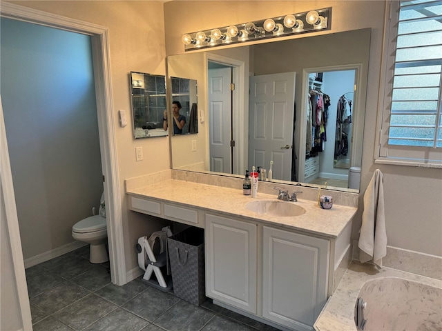 bathroom featuring tile patterned floors, vanity, toilet, and a bathing tub