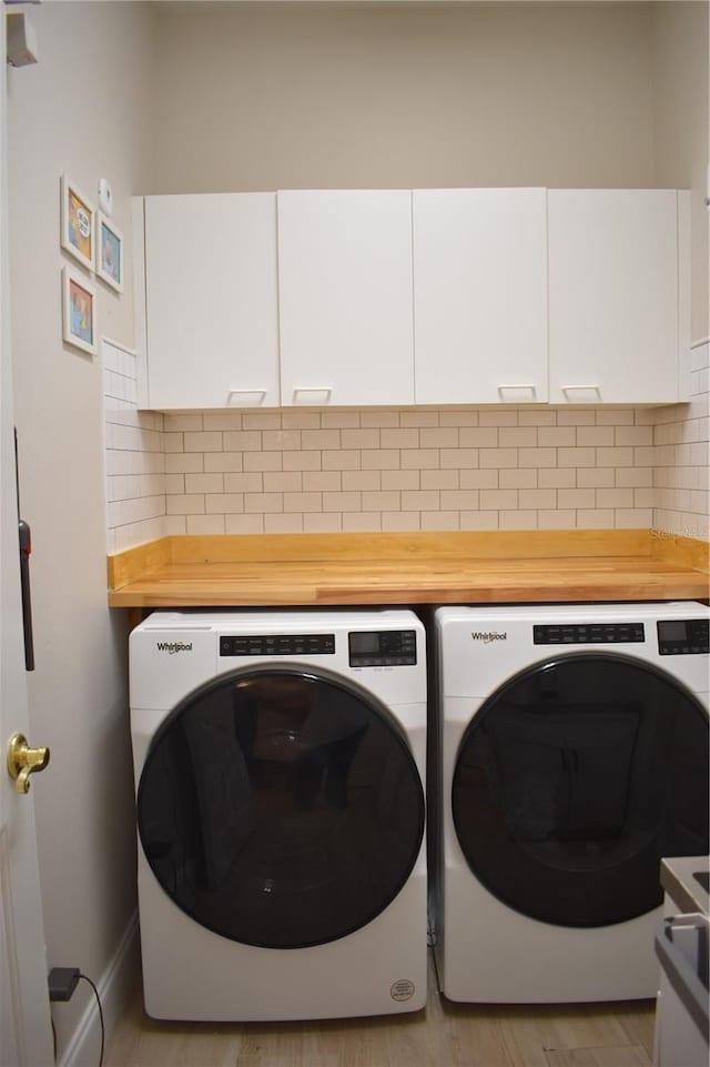 clothes washing area featuring light hardwood / wood-style floors, cabinets, and washing machine and clothes dryer