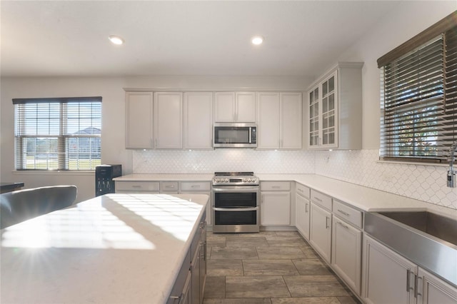 kitchen featuring backsplash, appliances with stainless steel finishes, sink, and gray cabinetry