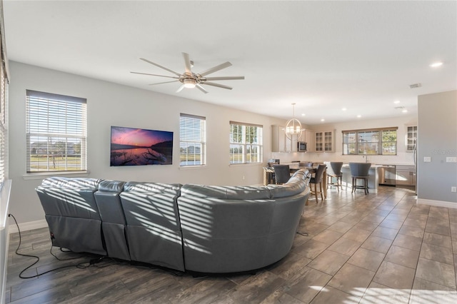 living room featuring ceiling fan with notable chandelier and plenty of natural light