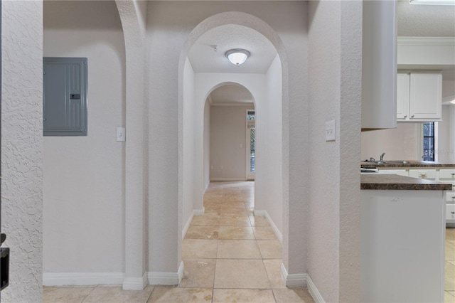 corridor featuring ornamental molding, light tile patterned floors, electric panel, and a textured ceiling