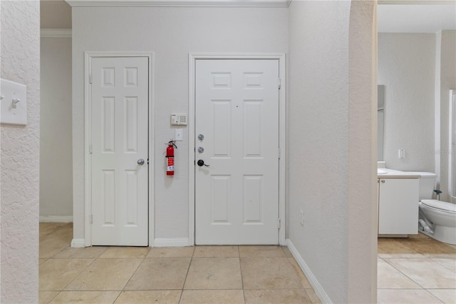 foyer featuring ornamental molding and light tile patterned floors