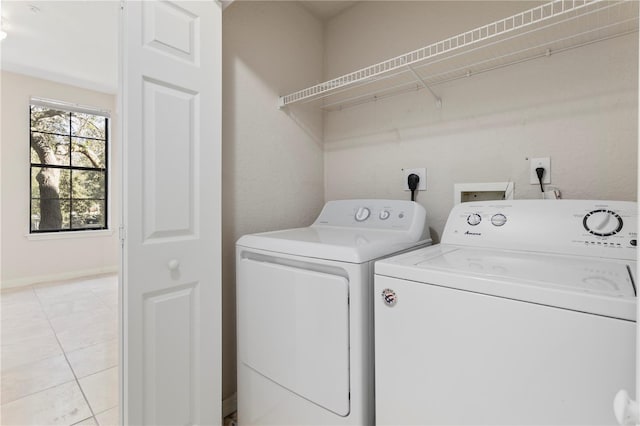 clothes washing area with washing machine and dryer and light tile patterned floors