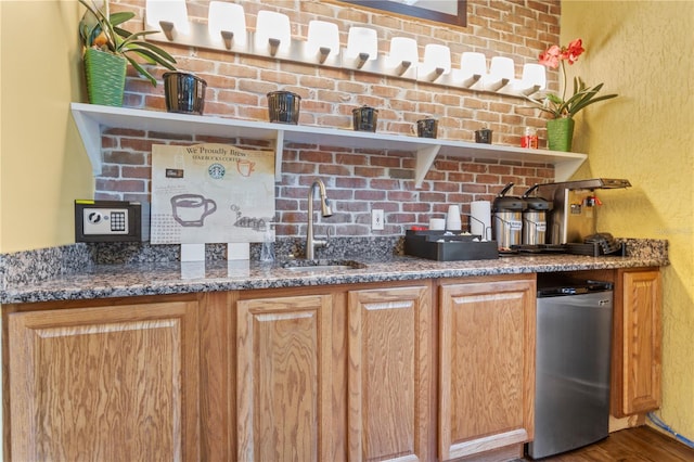 kitchen featuring dishwasher, sink, dark stone countertops, hardwood / wood-style flooring, and fridge