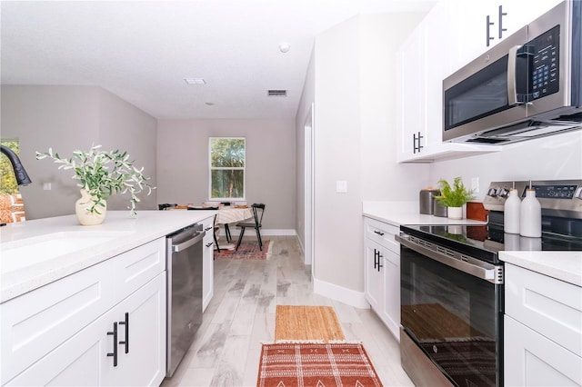 kitchen featuring appliances with stainless steel finishes, light hardwood / wood-style floors, sink, and white cabinets