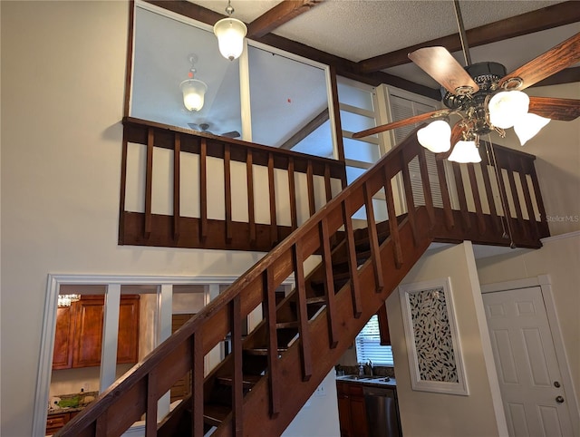 staircase featuring sink, a textured ceiling, beamed ceiling, and ceiling fan