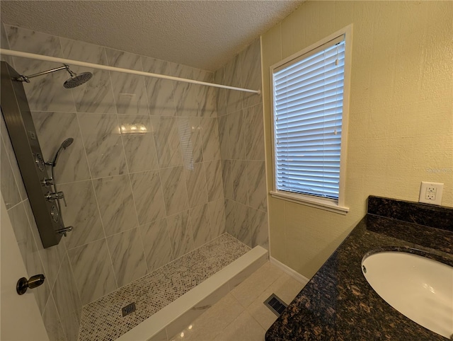 bathroom featuring vanity, plenty of natural light, a textured ceiling, and tiled shower