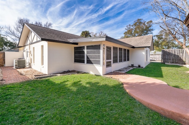 rear view of property with a sunroom, central AC unit, and a lawn