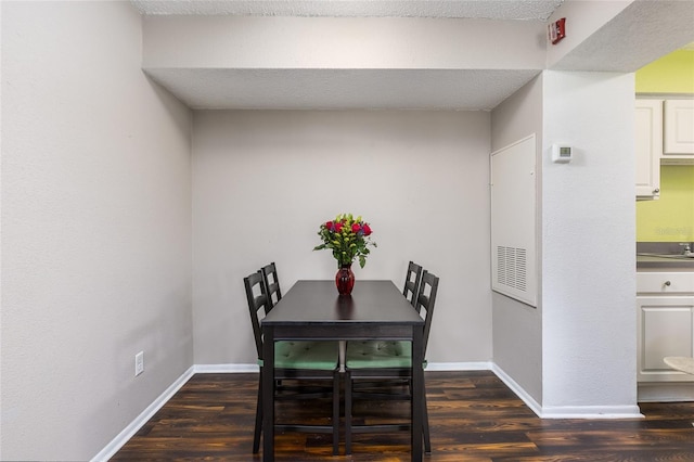 dining room featuring dark wood-type flooring and a textured ceiling