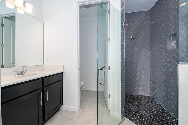 bathroom featuring tile patterned flooring, vanity, tiled shower, and toilet