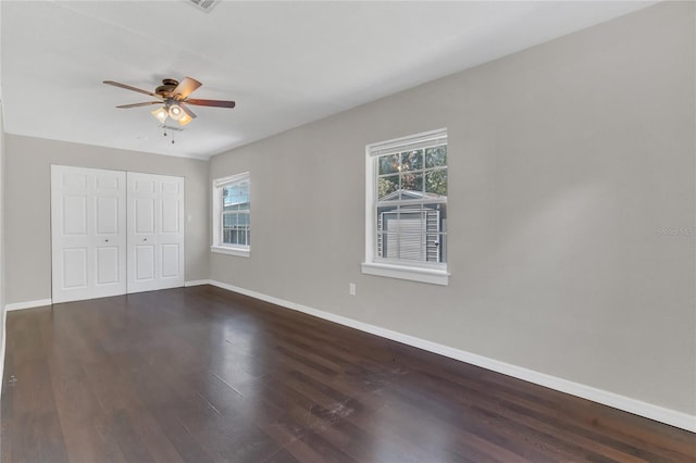 unfurnished bedroom with dark wood-type flooring, ceiling fan, and a closet