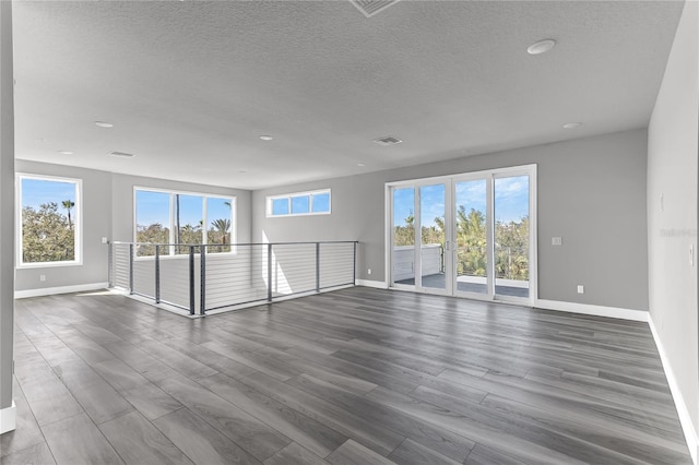 spare room featuring dark hardwood / wood-style flooring and a textured ceiling