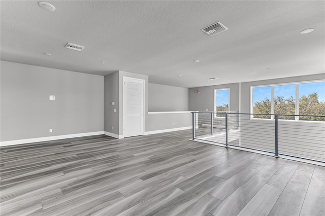 empty room with light hardwood / wood-style flooring and a textured ceiling