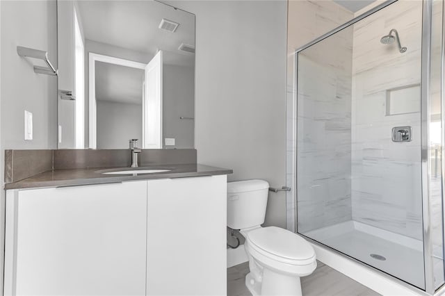 bathroom featuring vanity, toilet, and a shower with door