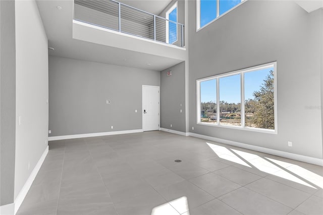 unfurnished living room with light tile patterned floors and a high ceiling