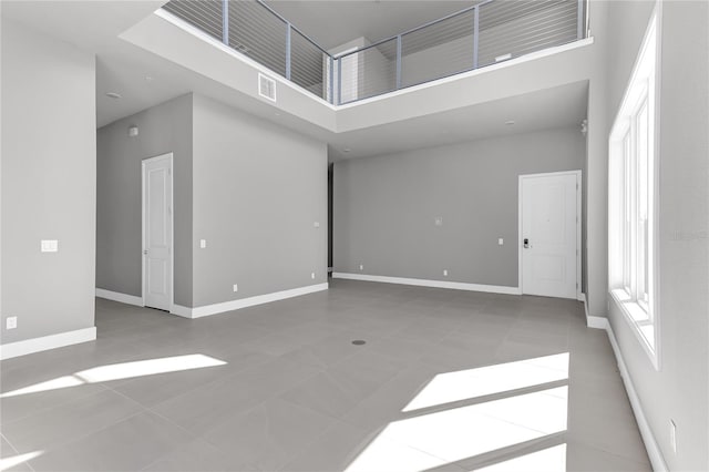 empty room with a high ceiling and tile patterned flooring