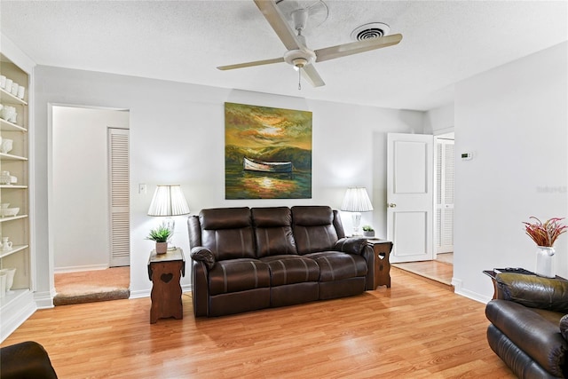 living room with light hardwood / wood-style flooring, built in features, and a textured ceiling