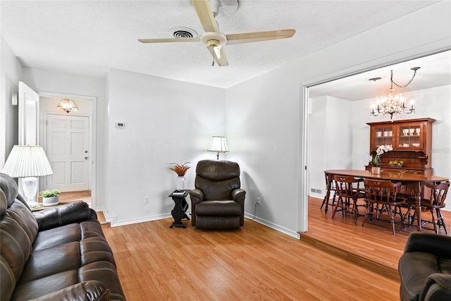 living room with hardwood / wood-style floors, ceiling fan with notable chandelier, and a textured ceiling