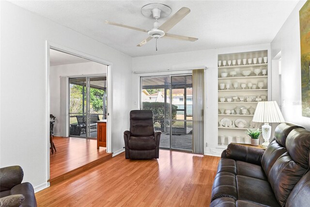 living room with hardwood / wood-style flooring, ceiling fan, plenty of natural light, and built in shelves