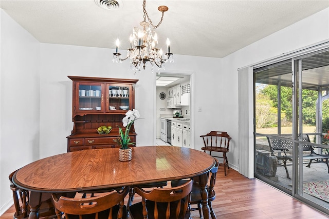 dining area with an inviting chandelier and light hardwood / wood-style floors