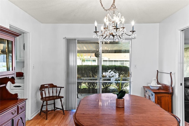 dining area with an inviting chandelier, light hardwood / wood-style flooring, and a textured ceiling