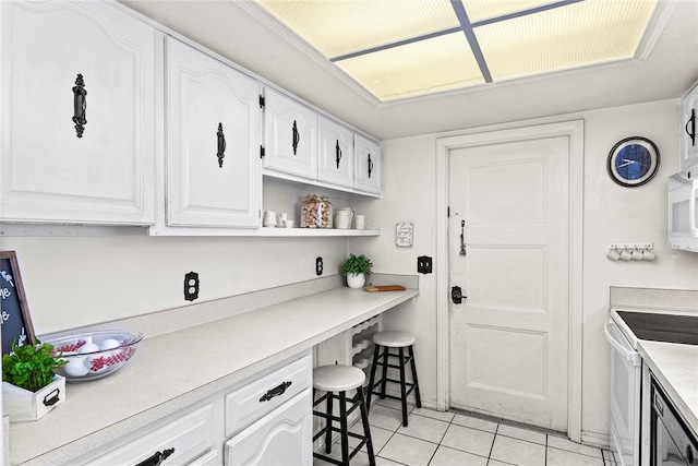 kitchen with white cabinetry, light tile patterned floors, and electric stove