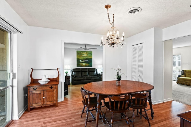 dining area featuring an inviting chandelier, a textured ceiling, and light hardwood / wood-style flooring