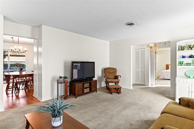 carpeted living room with a chandelier and a textured ceiling