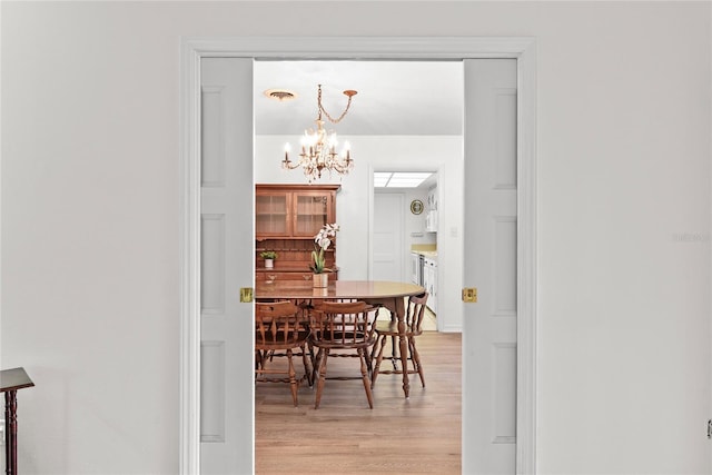 dining area with light wood-type flooring, a chandelier, and visible vents
