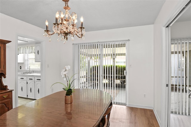 dining area with baseboards, light wood finished floors, a notable chandelier, and a wealth of natural light