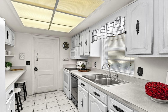 kitchen with a sink, light tile patterned floors, white cabinets, light countertops, and white appliances