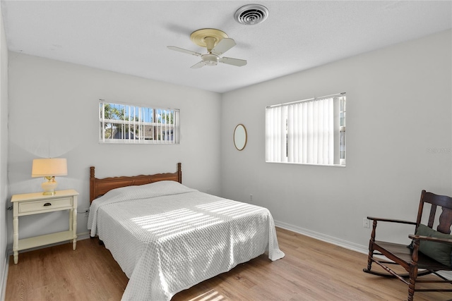 bedroom with baseboards, ceiling fan, wood finished floors, and visible vents